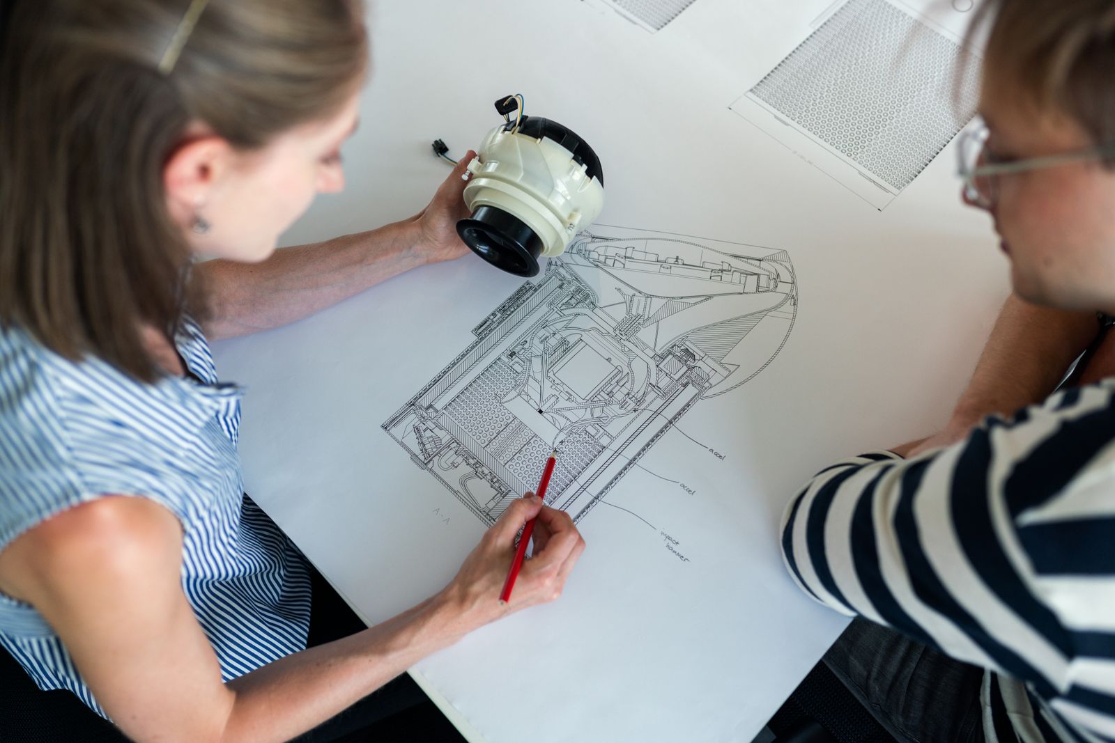 Engineers reviewing a technical drawing and component together.