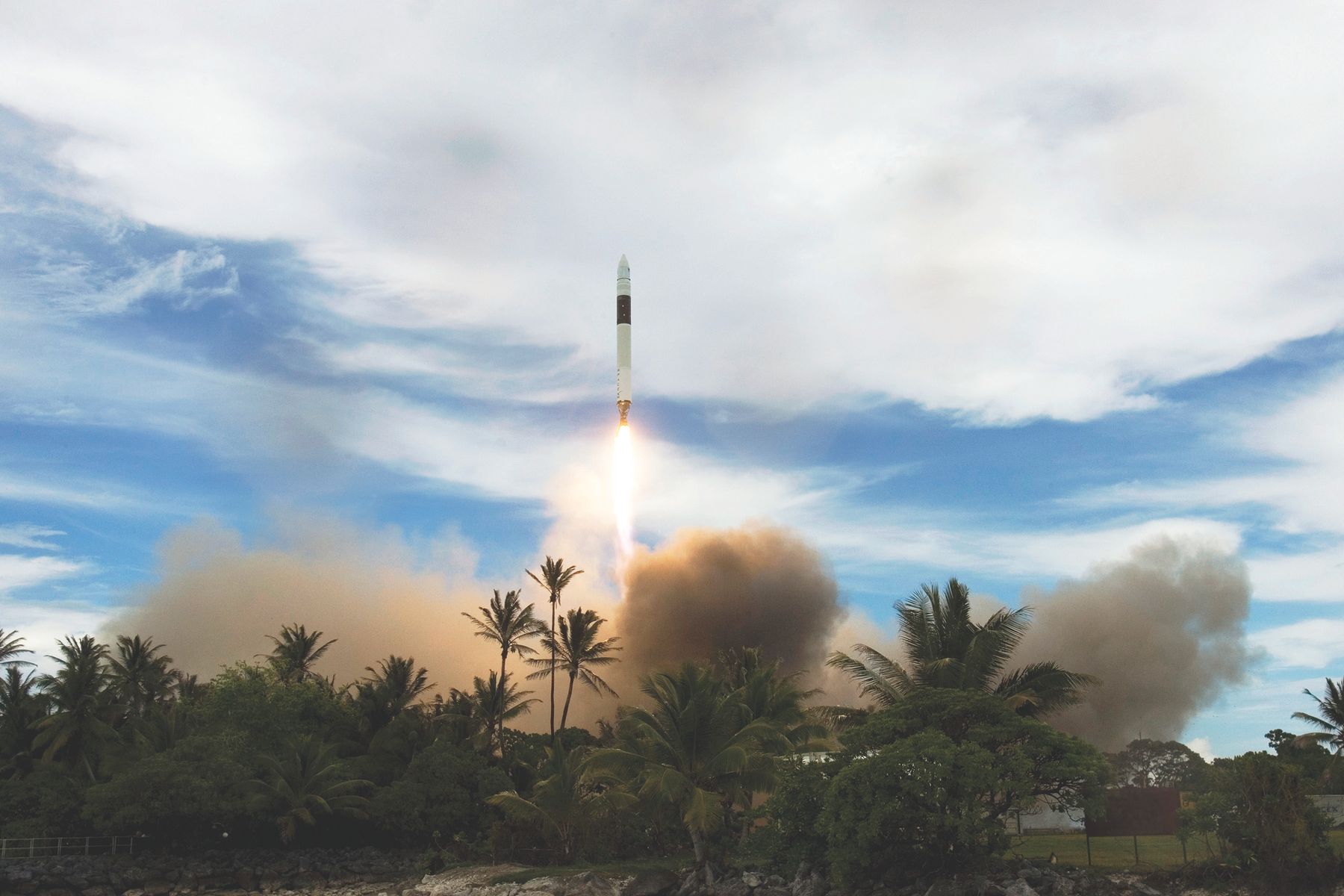 A rocket ascending above the launch site with a bright exhaust plume.