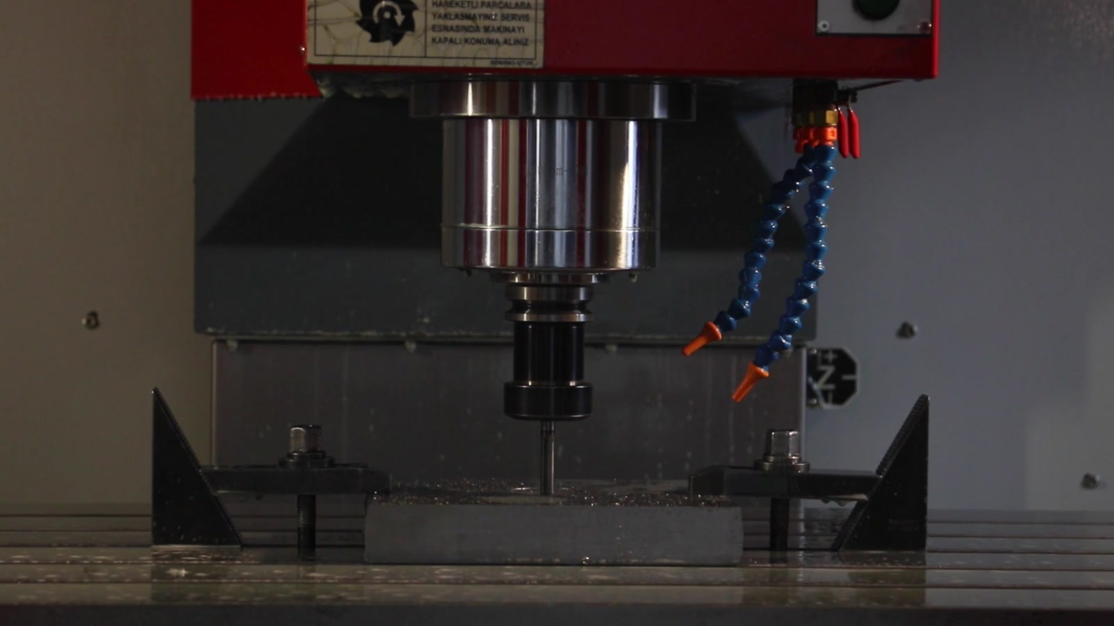 Spindle, tooling, and machine bed inside an enclosed CNC machining center.